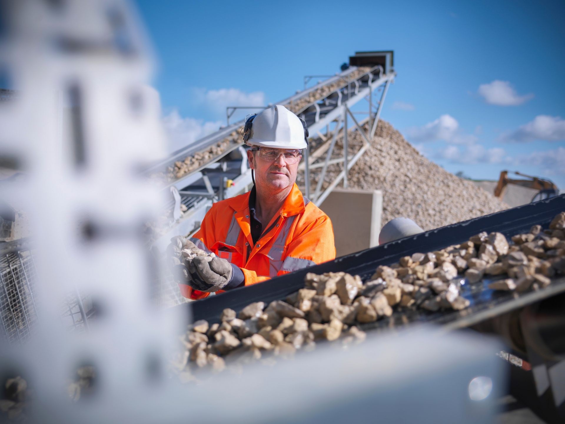 Worker inspecting stone screening and crushing machine in quarry Worker inspecting stone screening and crushing machine in quarry